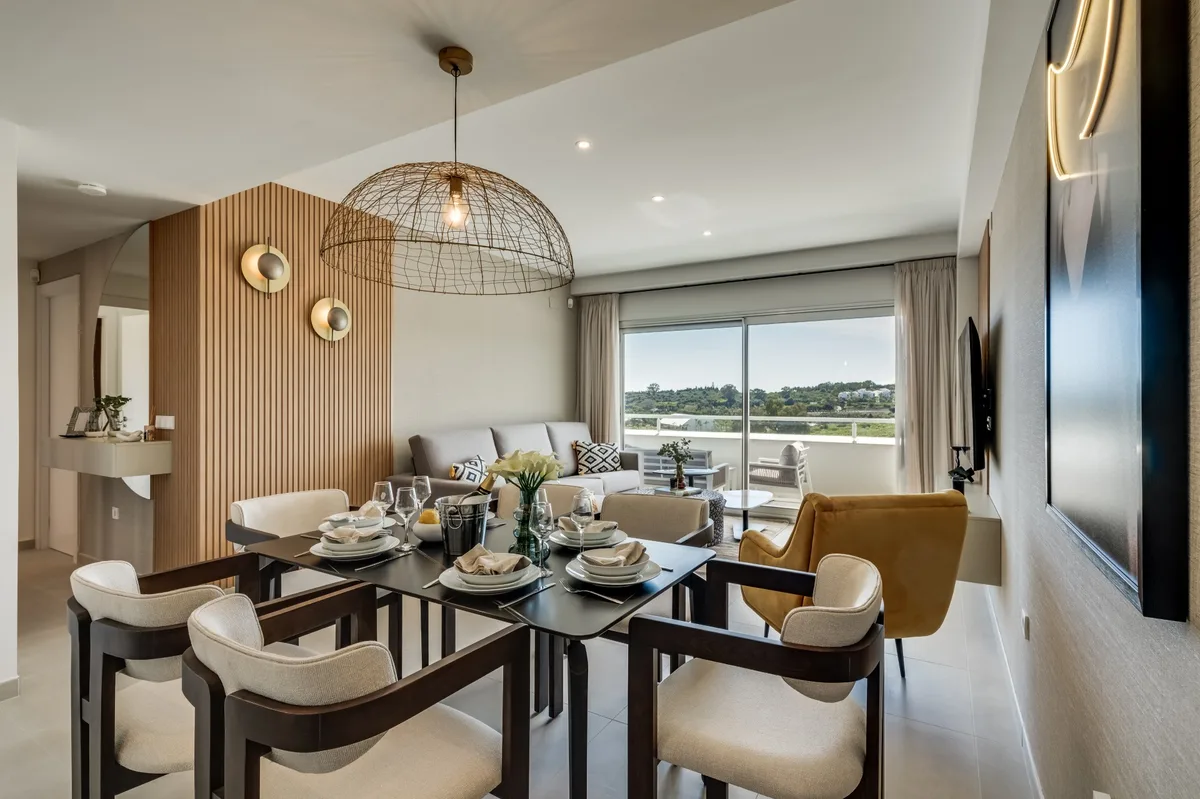 Living and dining room of Casa Vierosa, with a laid table and a terrace overlooking the golf course